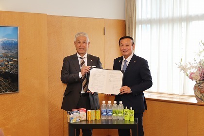 写真：大塚製薬の製品を前に締結書を手にする市長